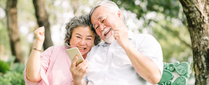 Happy senior Asian couple using smartphone